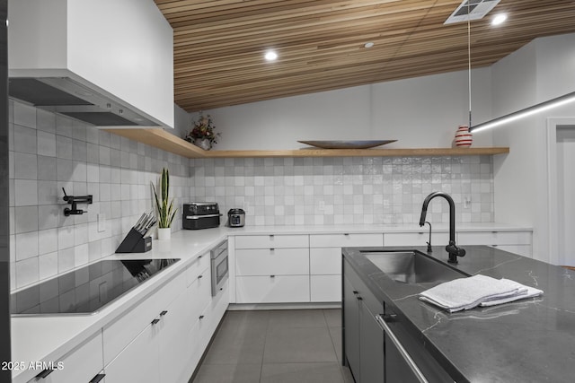 kitchen featuring black electric cooktop, a sink, custom exhaust hood, and open shelves