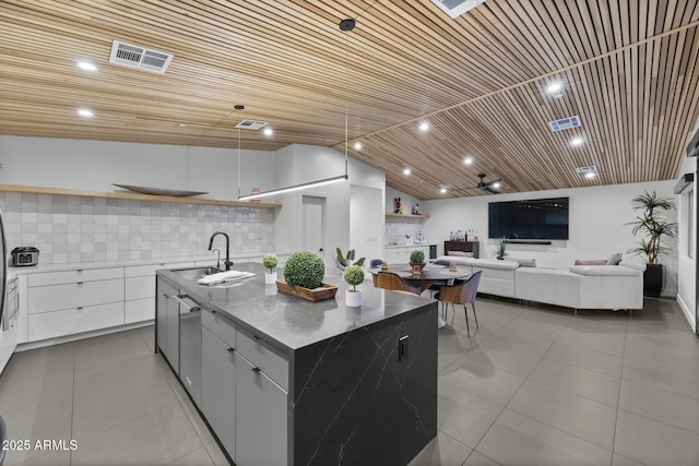 kitchen with a center island with sink, visible vents, modern cabinets, open shelves, and a sink