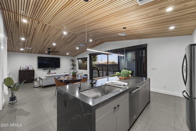 kitchen with dishwasher, open floor plan, freestanding refrigerator, a kitchen island with sink, and a sink