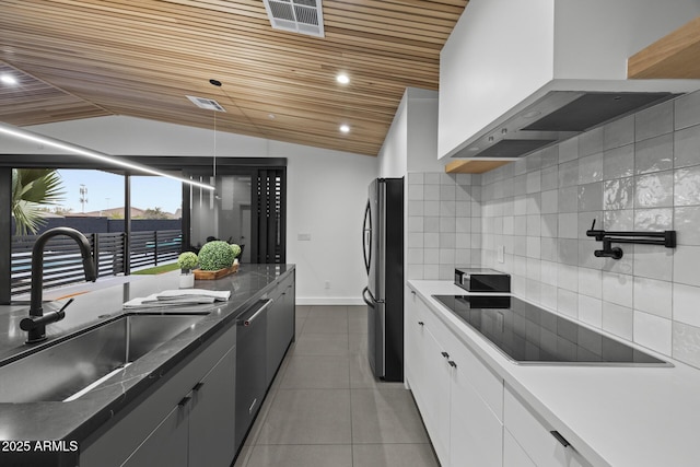 kitchen with a sink, tile patterned flooring, stainless steel appliances, wall chimney range hood, and backsplash