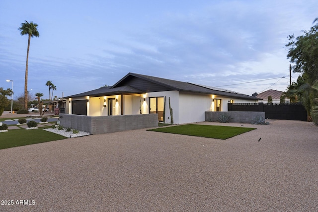 view of front of house featuring a front lawn, a patio, an attached garage, and fence