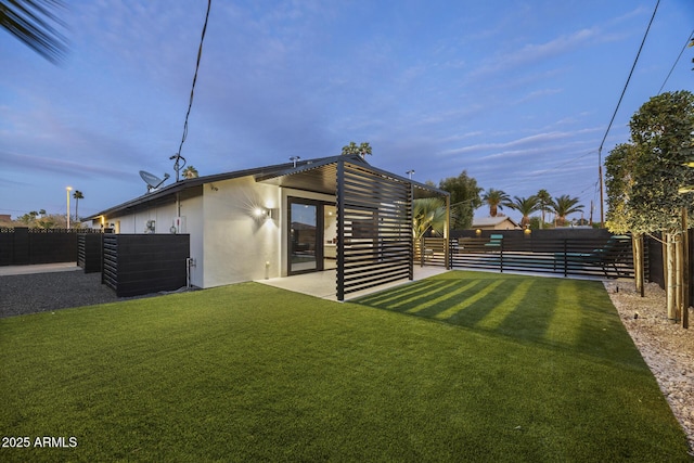 back of property featuring a yard, a fenced backyard, and stucco siding