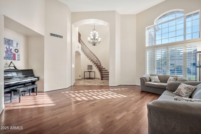 15413 S 31st Pl, Phoenix, AZ 85048 - living area featuring a chandelier, a towering ceiling, arched walkways, visible vents, and wood finished floors