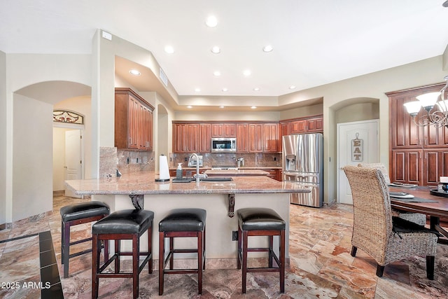 15413 S 31st Pl, Phoenix, AZ 85048 - kitchen with a kitchen bar, stainless steel appliances, a sink, arched walkways, and a peninsula