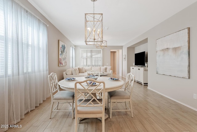 dining space with light wood-style flooring, baseboards, and a notable chandelier