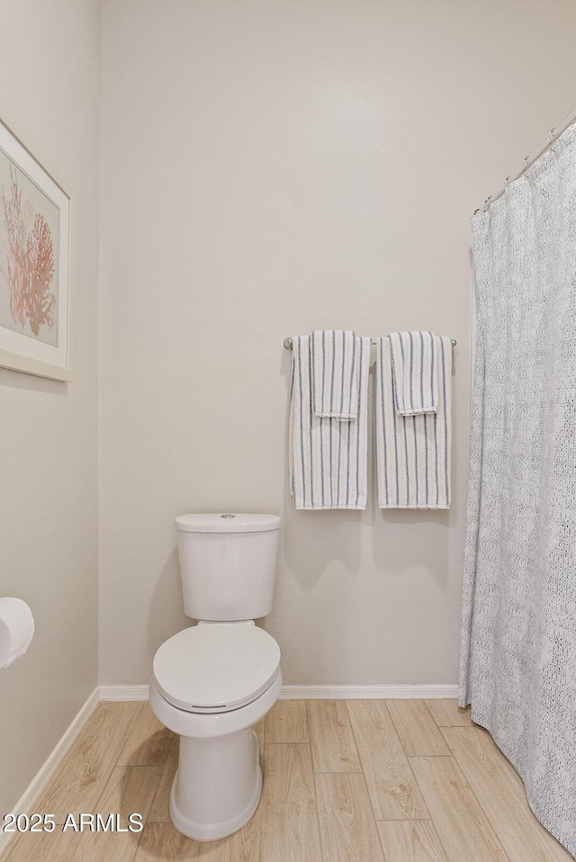 full bath featuring curtained shower, toilet, baseboards, and wood finished floors