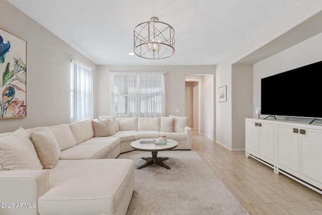 living room featuring a chandelier, light wood-type flooring, and baseboards