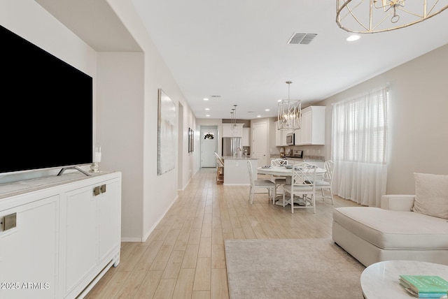 living room featuring light wood-style floors, visible vents, a chandelier, and recessed lighting