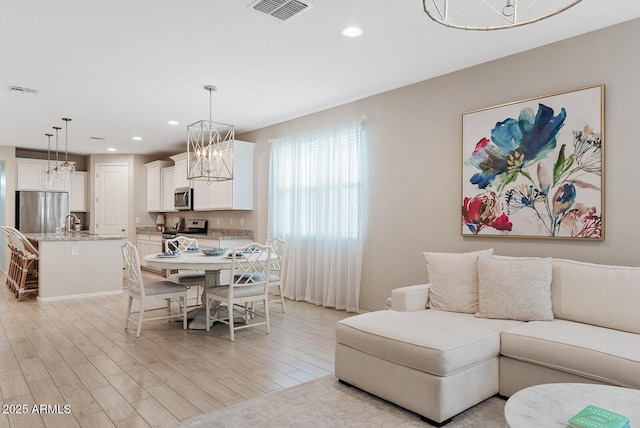 dining room with recessed lighting, visible vents, light wood finished floors, and an inviting chandelier