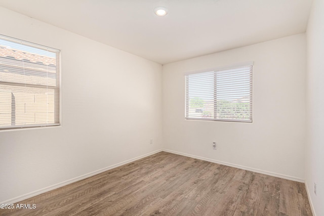 empty room featuring a wealth of natural light, light wood-style flooring, and baseboards
