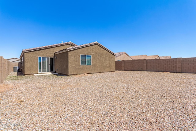 back of property with a fenced backyard, stucco siding, and a tile roof