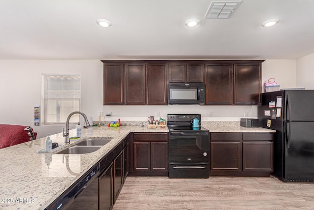 kitchen with dark brown cabinetry, black appliances, light wood-type flooring, a sink, and visible vents