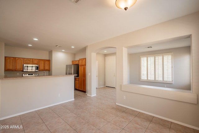 unfurnished living room with arched walkways, recessed lighting, baseboards, light tile patterned floors, and visible vents