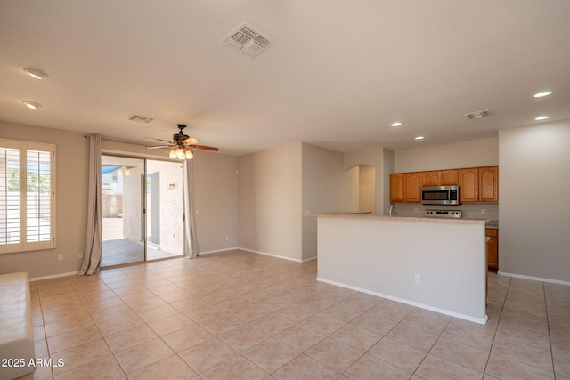 kitchen featuring recessed lighting, stainless steel microwave, light tile patterned floors, and visible vents