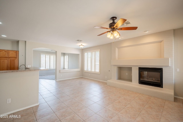 unfurnished living room featuring light tile patterned floors, a glass covered fireplace, and a wealth of natural light