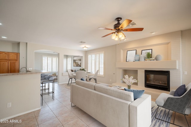 living room featuring light tile patterned floors, a glass covered fireplace, a healthy amount of sunlight, and visible vents
