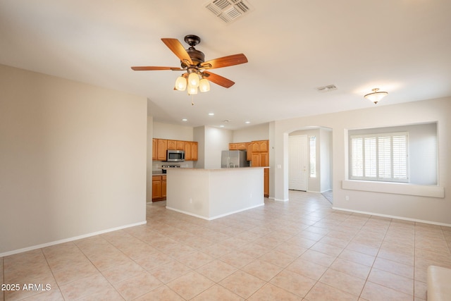 unfurnished living room featuring light tile patterned floors, arched walkways, a ceiling fan, and visible vents