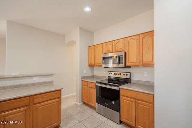 kitchen with light countertops, arched walkways, stainless steel appliances, recessed lighting, and light tile patterned floors