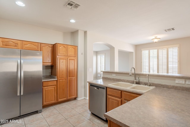kitchen featuring arched walkways, appliances with stainless steel finishes, a sink, and visible vents