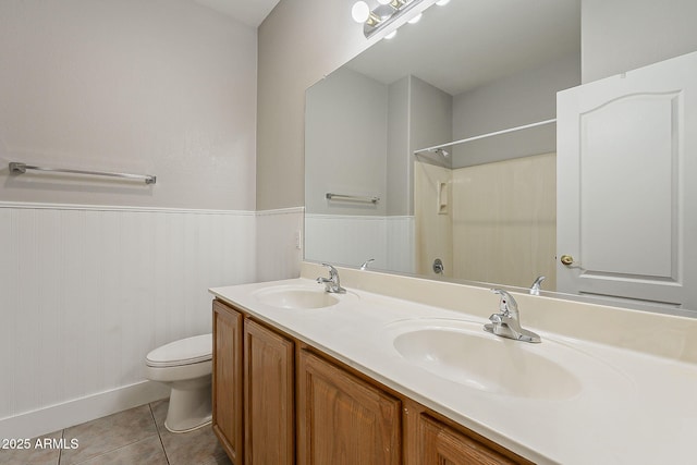 full bath with a sink, wainscoting, toilet, and double vanity
