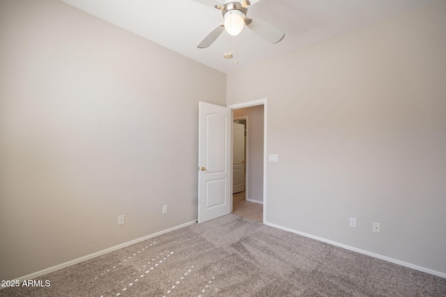 carpeted spare room with a ceiling fan and baseboards