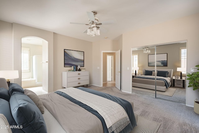 bedroom with arched walkways, baseboards, light carpet, and multiple windows