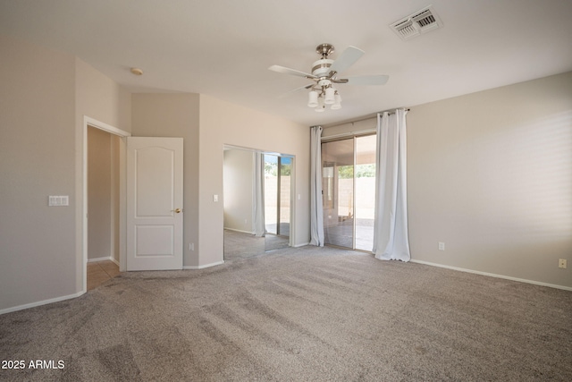spare room with carpet floors, baseboards, a ceiling fan, and visible vents