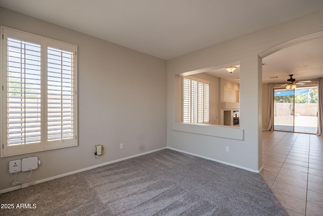 spare room featuring baseboards, a ceiling fan, and carpet flooring