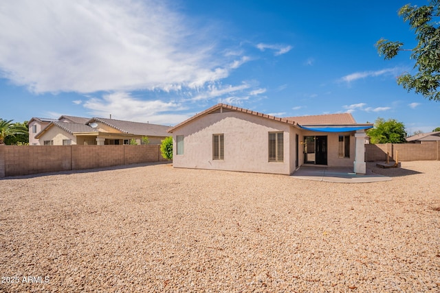 rear view of house with a fenced backyard, a patio, stucco siding, and a tiled roof