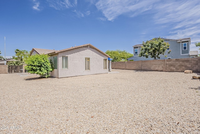 rear view of house with a fenced backyard and stucco siding