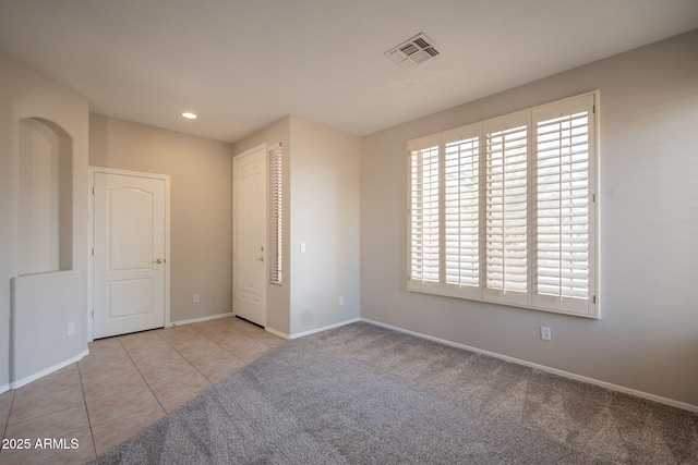 unfurnished bedroom with visible vents, baseboards, tile patterned floors, carpet, and recessed lighting