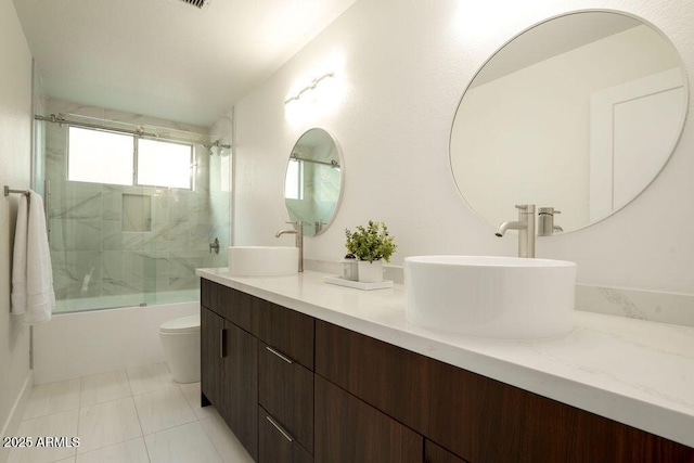 full bathroom featuring bath / shower combo with glass door, vanity, tile patterned floors, and toilet