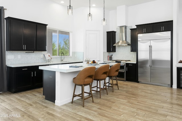 6133 E Dixileta Dr, Cave Creek, AZ 85331 - kitchen featuring high end appliances, wall chimney exhaust hood, a high ceiling, dark cabinetry, and decorative backsplash