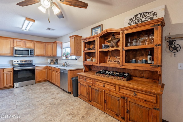 kitchen with appliances with stainless steel finishes, a textured ceiling, ceiling fan, and sink