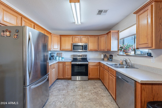 kitchen with a textured ceiling, stainless steel appliances, and sink