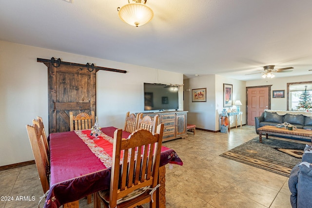 dining area with a barn door and ceiling fan