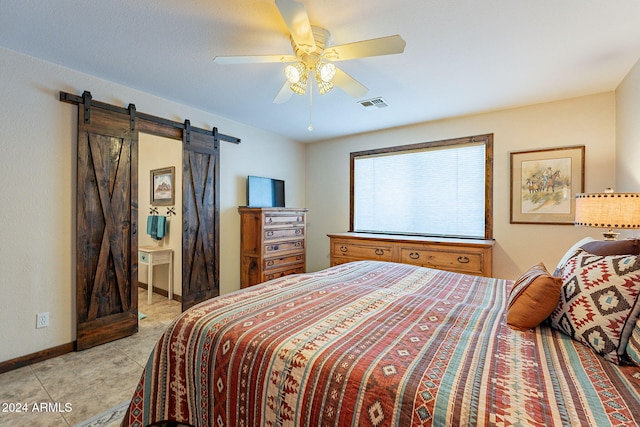 bedroom with ceiling fan, a barn door, and light tile patterned floors