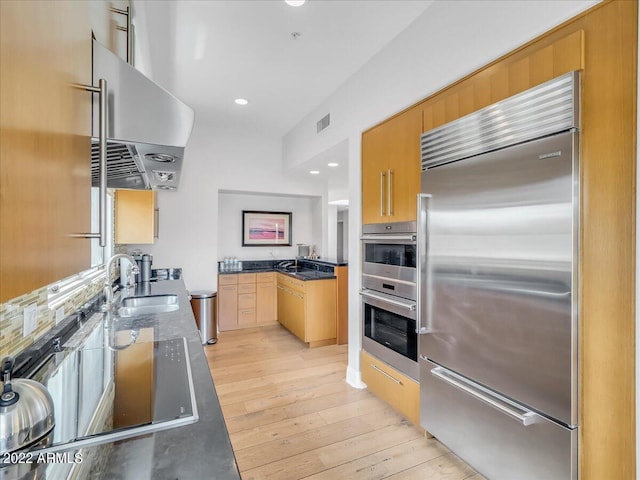 kitchen featuring sink, stainless steel appliances, extractor fan, light hardwood / wood-style floors, and light brown cabinets