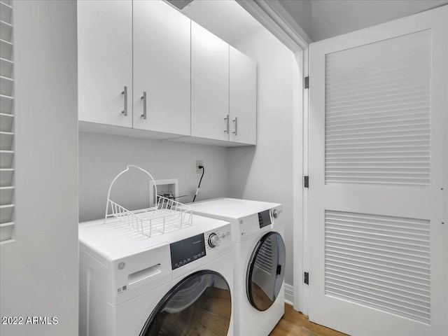 washroom featuring cabinets, separate washer and dryer, and light hardwood / wood-style floors