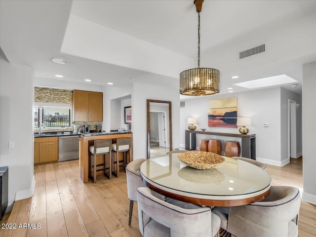 dining room featuring a chandelier, sink, and light hardwood / wood-style flooring