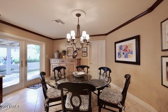 dining area featuring crown molding, light tile patterned flooring, a notable chandelier, and french doors