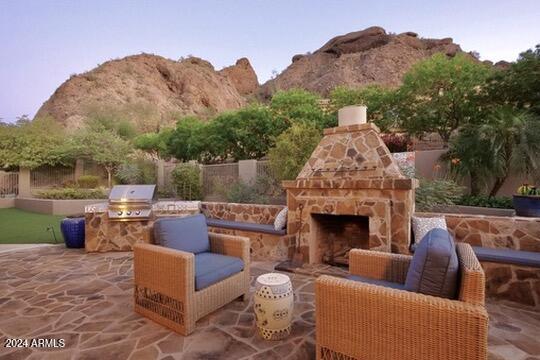 view of patio / terrace with exterior kitchen, a mountain view, a grill, and an outdoor stone fireplace