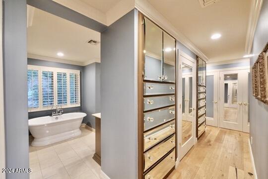 bathroom featuring a tub, crown molding, and hardwood / wood-style floors