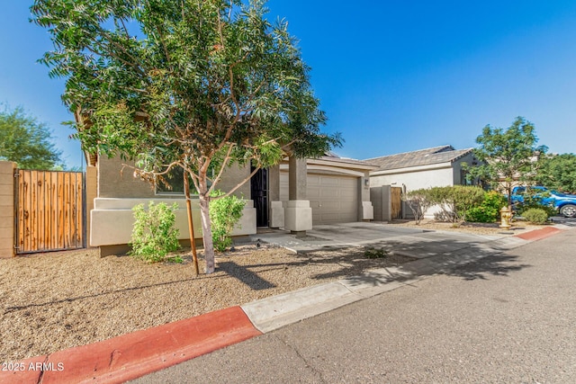 1940 W Expressman St, Apache Junction, AZ 85120 - obstructed view of property with stucco siding, an attached garage, driveway, and a gate