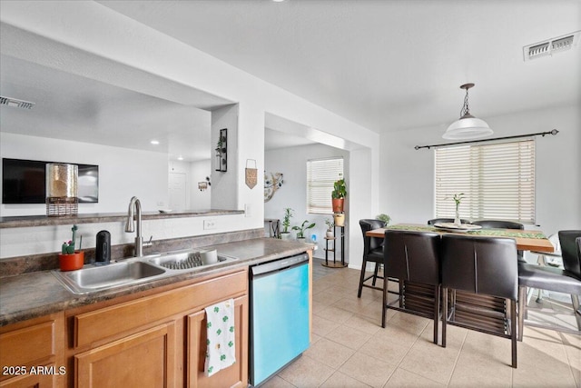 kitchen with light tile patterned floors, dishwashing machine, a sink, visible vents, and brown cabinets