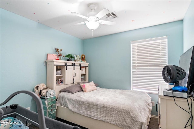 bedroom with baseboards, wood finished floors, visible vents, and a ceiling fan