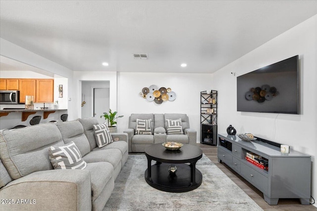 living room with wood finished floors, visible vents, and recessed lighting