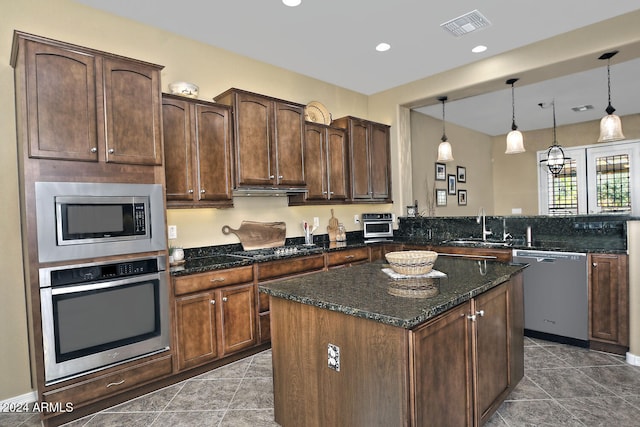 kitchen featuring sink, kitchen peninsula, dark stone countertops, pendant lighting, and appliances with stainless steel finishes