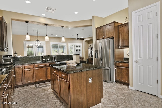 kitchen with a center island, hanging light fixtures, appliances with stainless steel finishes, and dark stone counters