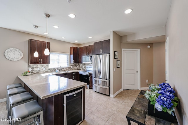 kitchen featuring pendant lighting, a breakfast bar area, appliances with stainless steel finishes, wine cooler, and kitchen peninsula